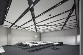 Lichtbandsysteme beleuchten einen Sitzungssaal mit Reihenbestuhlung. Beleuchtungsniveau und Lichtfarbe können gesteuert werden. 