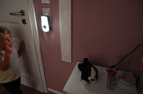 Ein Kind steht vor der Tür seines Kinderzimmers und schaut zur leuchtenden Steckdosenleuchte.