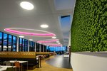 In der Kantine mit großen Fensterflächen und Oberlichtern für den Tageslichteinfall sind die großformatigen runden Leuchten mit farbigem Licht der Blickfang. Sie werden intelligent mit einem Lichtmanagementsystem gesteuert.
