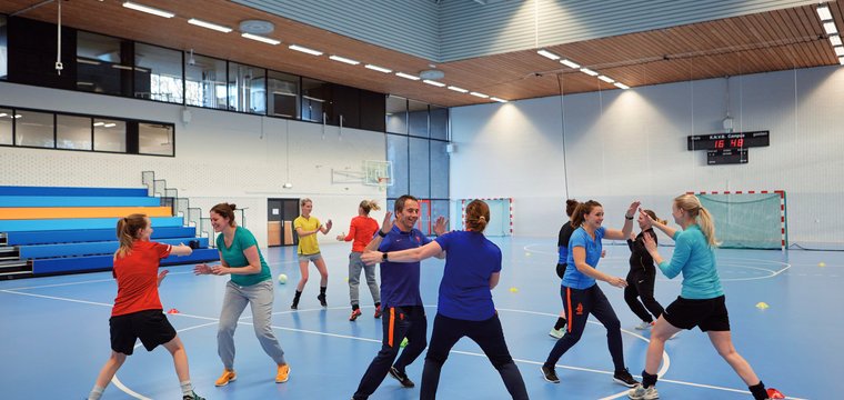 In einer Sporthalle trainieren fünf Paare Angriff und Täuschung beim Ballsport.