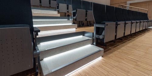 Die Treppe zur ansteigenden Bestuhlung des Veranstaltungsraums ist beleuchtet.