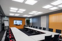 Konferenzraum mit U-förmiger Anordnung der Arbeitstische und  Präsentationsbildschirm an der stirnseitigen Wand: Quadratische Deckeneinbauleuchten schaffen ausreichend Helligkeit auf den horizontalen Tischflächen und vermeiden Blendung auf dem Display.  