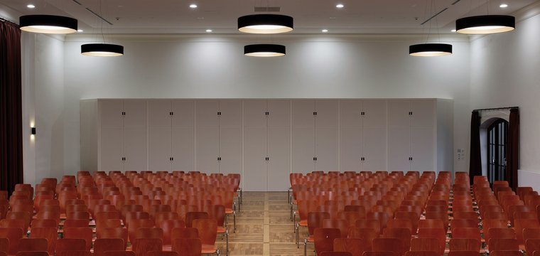 Im Vortragsraum ermöglichen runde Deckenleuchten und zusätzliche Einbau-Downlights bedarfsgerechte Beleuchtung für unterschiedliche Nutzungen.