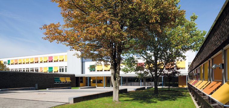 Der überdachte Eingangsbereich einer Schule ist mit runden Deckenanbauleuchten ausgestattet. 